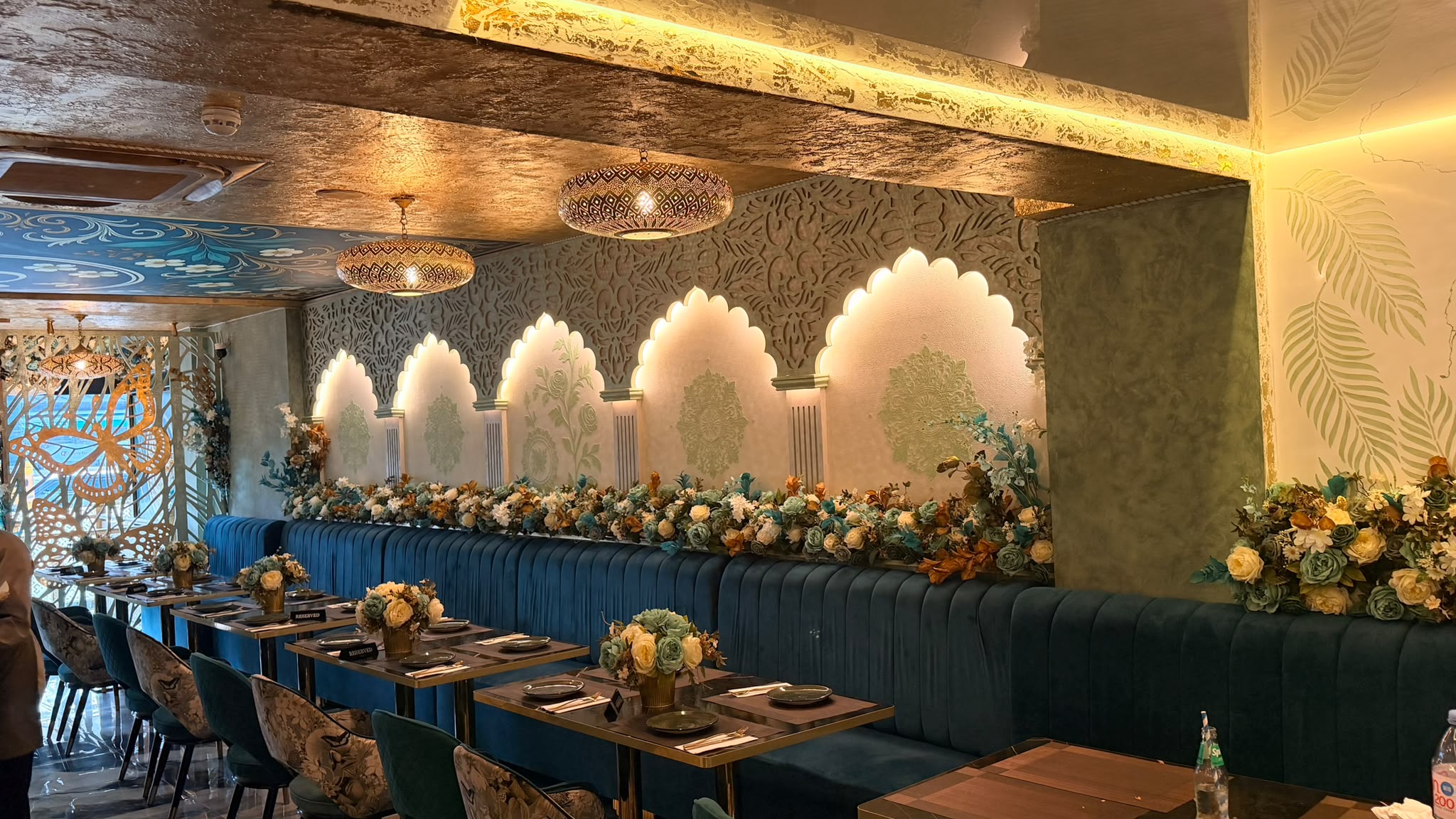 Warmly lit Bagh dining room with floral seating and decorative arches